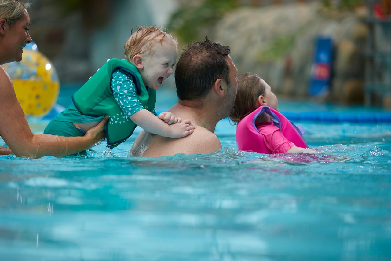 A family swimming in the indoor swimming pool.